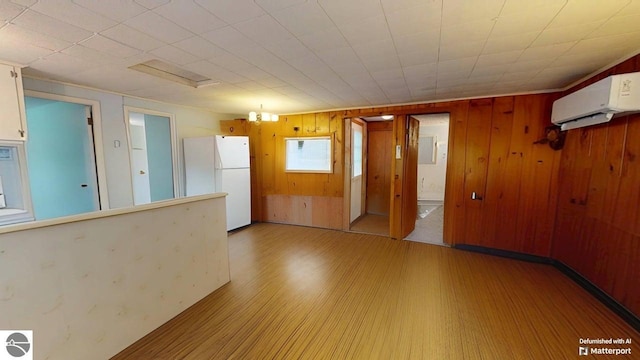 921 Pine St, Harrison, MI 48625 - spare room with a wall mounted air conditioner, light wood-style floors, wood walls, and electric panel