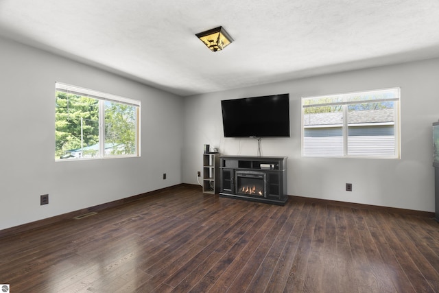 4267 Main St, Kingsley, MI 49649 - unfurnished living room with wood finished floors, a glass covered fireplace, and baseboards