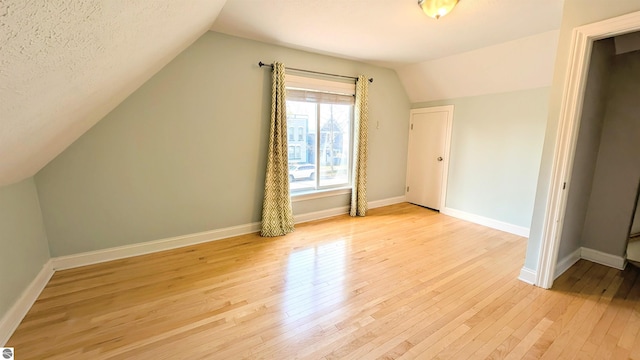 314 W Ninth St, Traverse City, MI 49684 - additional living space with light wood-type flooring, vaulted ceiling, and baseboards