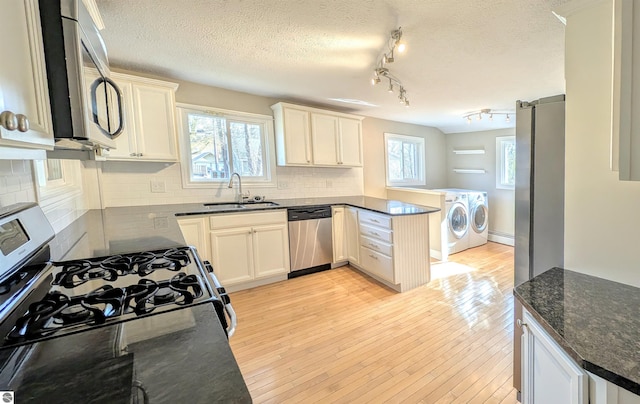 314 W Ninth St, Traverse City, MI 49684 - kitchen featuring separate washer and dryer, stainless steel appliances, a sink, a peninsula, and backsplash