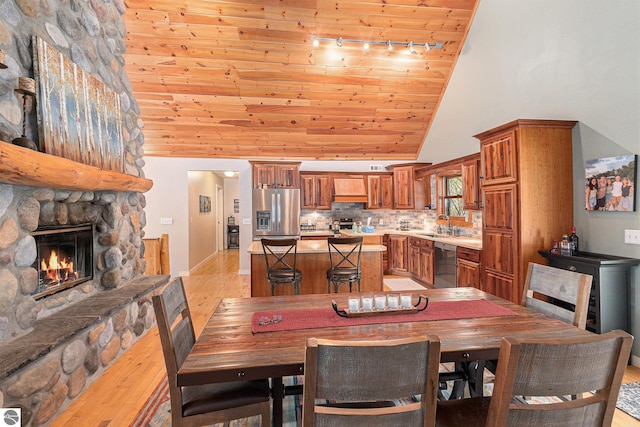 5301 Durga Rd, Williamsburg, MI 49690 - dining room with wood ceiling, high vaulted ceiling, track lighting, light wood-style floors, and a stone fireplace