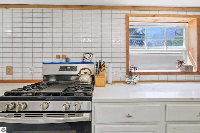 1493 NE Laura Ln, Kalkaska, MI 49646 - kitchen with stainless steel range with gas stovetop, decorative backsplash, white cabinets, and light stone counters