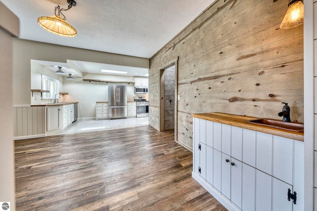 9560 S Cedar Rd, Cedar, MI 49621 - unfurnished living room featuring a sink, wooden walls, wood finished floors, and a textured ceiling