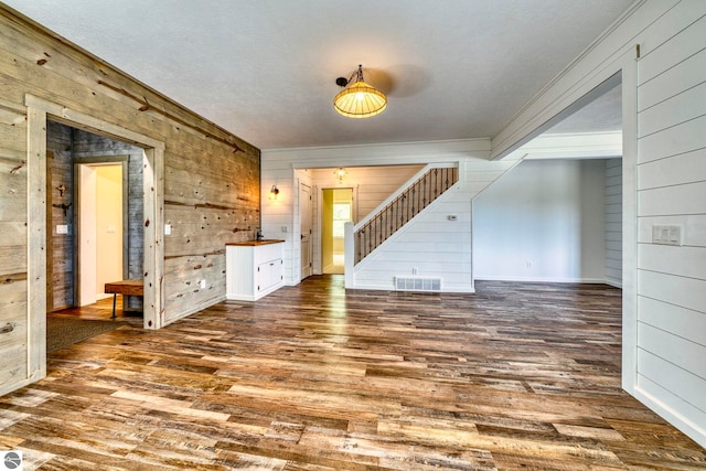 9560 S Cedar Rd, Cedar, MI 49621 - unfurnished living room with ornamental molding, wood walls, stairs, and wood finished floors