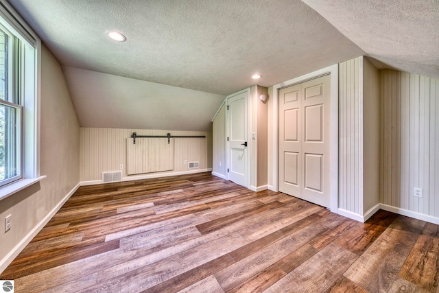 9560 S Cedar Rd, Cedar, MI 49621 - bonus room featuring a textured ceiling, wood finished floors, baseboards, vaulted ceiling, and recessed lighting