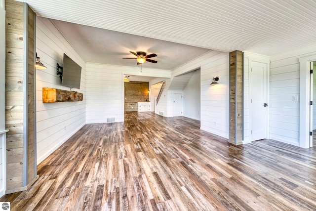 9560 S Cedar Rd, Cedar, MI 49621 - unfurnished living room featuring wood walls, wood finished floors, ceiling fan, and stairway