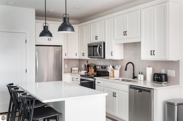 222 E State St Unit 303, Traverse City, MI 49684 - kitchen with stainless steel appliances, a sink, a breakfast bar, white cabinets, and decorative light fixtures