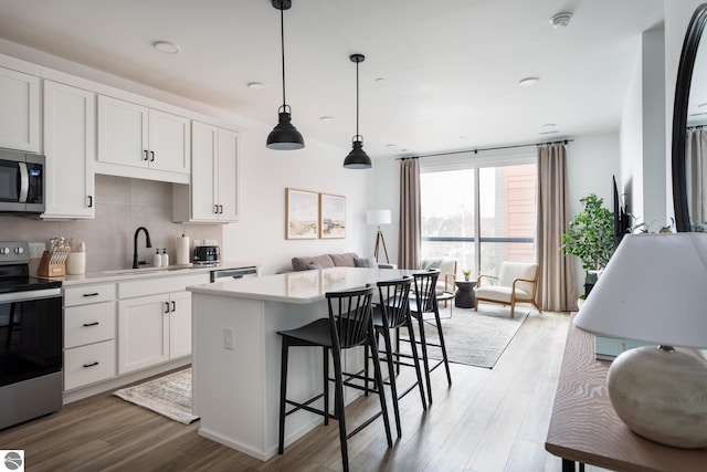 222 E State St Unit 303, Traverse City, MI 49684 - kitchen with appliances with stainless steel finishes, light wood finished floors, light countertops, a sink, and a center island
