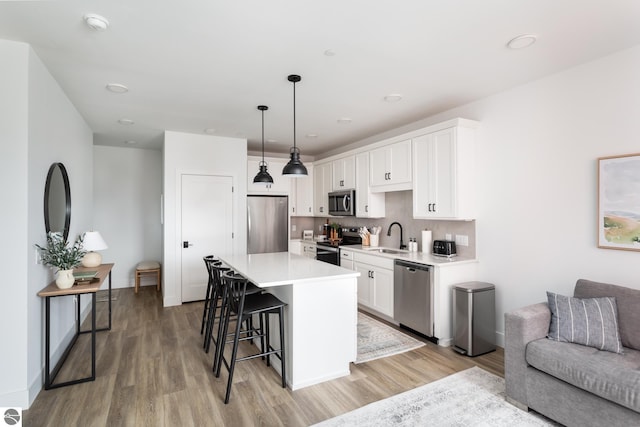 222 E State St Unit 303, Traverse City, MI 49684 - kitchen with appliances with stainless steel finishes, light wood-style floors, a kitchen bar, light countertops, and white cabinets