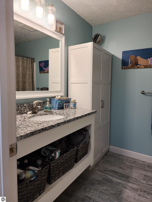 6368 Hardwood Dr, Lake Ann, MI 49650 - bathroom with a textured ceiling, vanity, wood finished floors, and baseboards