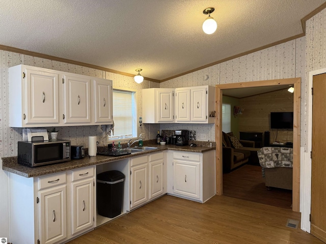 6661 Terry Ln, Hale, MI 48739 - kitchen featuring crown molding, stainless steel microwave, wallpapered walls, a textured ceiling, and dark countertops