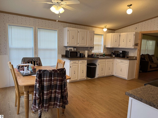 6661 Terry Ln, Hale, MI 48739 - kitchen with wallpapered walls, stainless steel microwave, crown molding, light wood-style flooring, and dark countertops