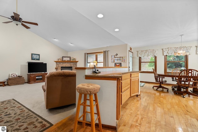 4611 Audubon Dr, Traverse City, MI 49686 - kitchen with ceiling fan, a fireplace, open floor plan, light countertops, and light wood-type flooring