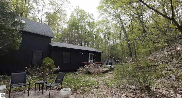 10092 S Elm St, Traverse City, MI 49684 - rear view of property featuring a shingled roof and a patio