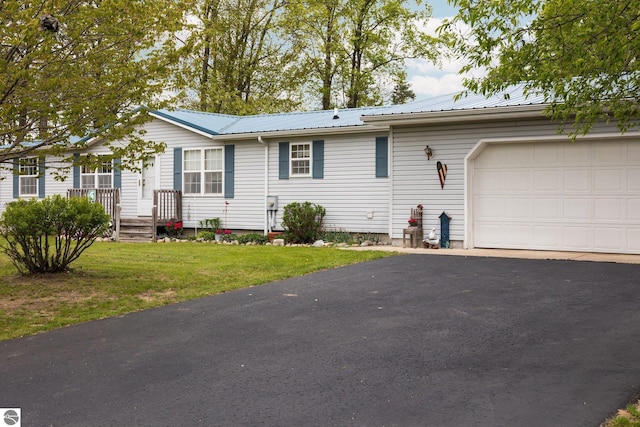 5206 S Riverview Dr, Lake City, MI 49651 - ranch-style home with an attached garage, asphalt driveway, metal roof, and a front yard