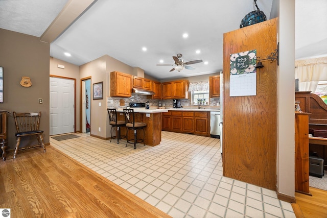 5206 S Riverview Dr, Lake City, MI 49651 - kitchen with a kitchen breakfast bar, under cabinet range hood, light countertops, lofted ceiling, and decorative backsplash