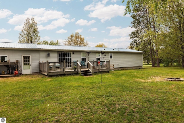 5206 S Riverview Dr, Lake City, MI 49651 - back of house featuring an outdoor fire pit, a wooden deck, a yard, and metal roof