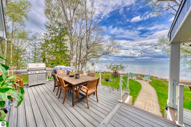 6433 S W Bayshore Dr, Traverse City, MI 49684 - wooden terrace featuring outdoor dining space, a water view, a grill, and a yard