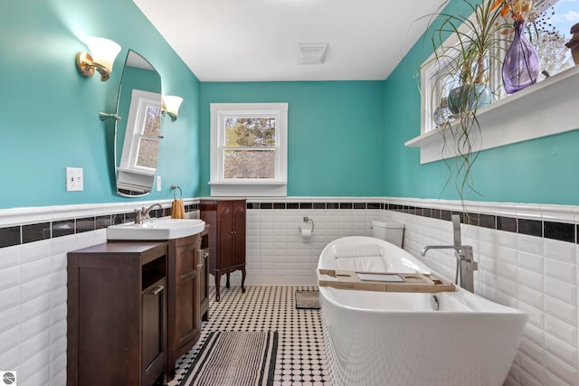 7256 Highland Dr, Beulah, MI 49617 - bathroom featuring tile walls, wainscoting, vanity, a soaking tub, and tile patterned floors