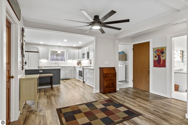 7256 Highland Dr, Beulah, MI 49617 - kitchen with stainless steel appliances, ceiling fan, washer / clothes dryer, light wood-style flooring, and light countertops