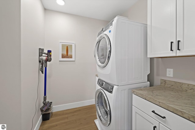 708 Randolph St Unit 204, Traverse City, MI 49684 - washroom featuring stacked washer / dryer, cabinet space, light wood-style floors, baseboards, and recessed lighting