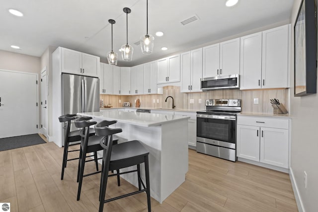 708 Randolph St Unit 204, Traverse City, MI 49684 - kitchen with stainless steel appliances, a breakfast bar area, light countertops, recessed lighting, and white cabinetry