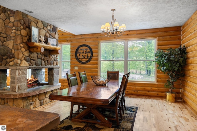 5592 Troon N, Bellaire, MI 49615 - dining area featuring a textured ceiling, hardwood / wood-style floors, a chandelier, rustic walls, and a stone fireplace