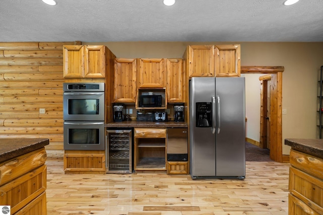 5592 Troon N, Bellaire, MI 49615 - kitchen featuring appliances with stainless steel finishes, wine cooler, log walls, a textured ceiling, and light wood-style flooring