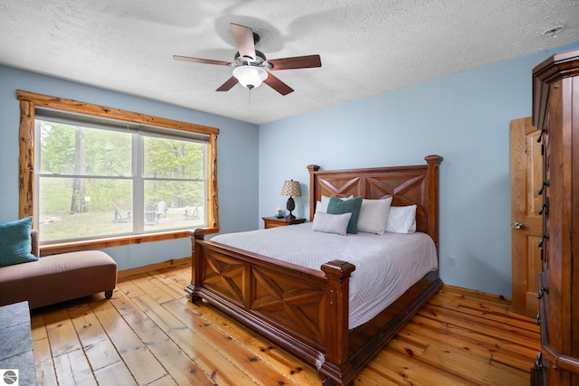 5592 Troon N, Bellaire, MI 49615 - bedroom featuring light wood-style floors, a textured ceiling, baseboards, and ceiling fan