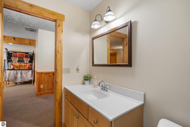 5592 Troon N, Bellaire, MI 49615 - half bathroom featuring vanity, wooden walls, wainscoting, and toilet