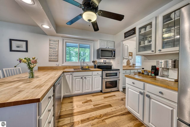 310 W Broadway, Suttons Bay, MI 49682 - kitchen with butcher block countertops, stainless steel appliances, a sink, glass insert cabinets, and a peninsula