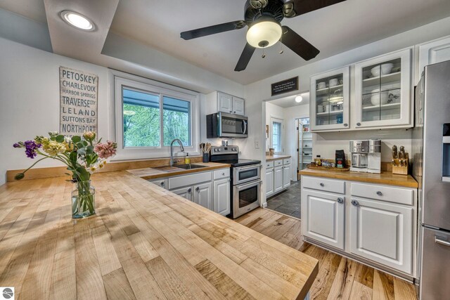 310 W Broadway, Suttons Bay, MI 49682 - kitchen featuring stainless steel appliances, wood counters, a sink, and white cabinets