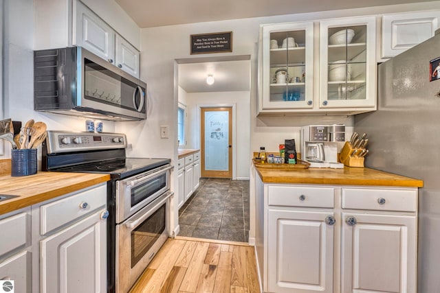310 W Broadway, Suttons Bay, MI 49682 - kitchen featuring appliances with stainless steel finishes, wooden counters, white cabinets, and glass insert cabinets