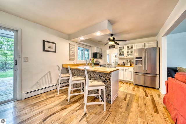 310 W Broadway, Suttons Bay, MI 49682 - kitchen with stainless steel appliances, a baseboard radiator, butcher block countertops, glass insert cabinets, and a kitchen bar