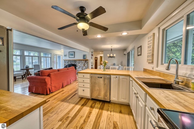 310 W Broadway, Suttons Bay, MI 49682 - kitchen featuring wood counters, dishwasher, a stone fireplace, stove, and light wood-style floors