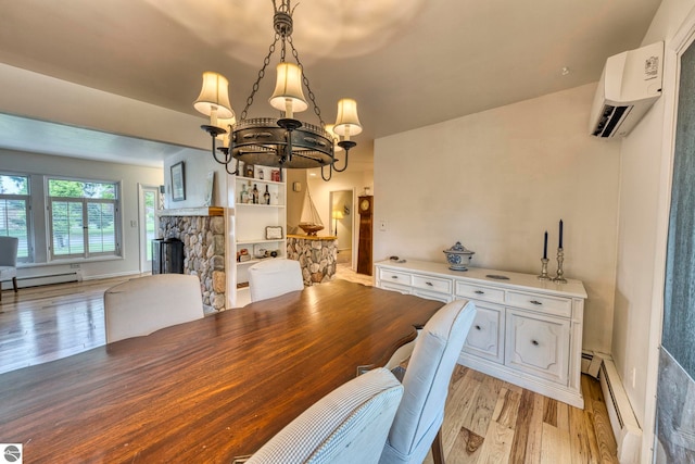 310 W Broadway, Suttons Bay, MI 49682 - dining area with a wall mounted AC, light wood-style flooring, a chandelier, a stone fireplace, and a baseboard radiator