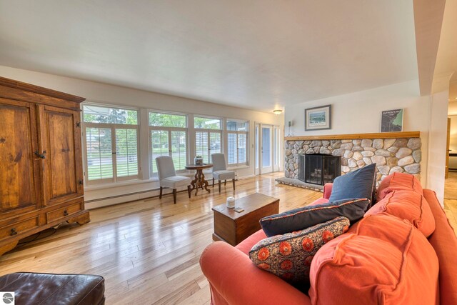 310 W Broadway, Suttons Bay, MI 49682 - living room with a baseboard radiator, healthy amount of natural light, a stone fireplace, and light wood-style floors