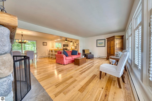 310 W Broadway, Suttons Bay, MI 49682 - living area featuring light wood-type flooring, a baseboard radiator, a ceiling fan, and a chandelier