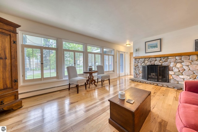 310 W Broadway, Suttons Bay, MI 49682 - living room with a baseboard radiator, light wood-type flooring, and a stone fireplace