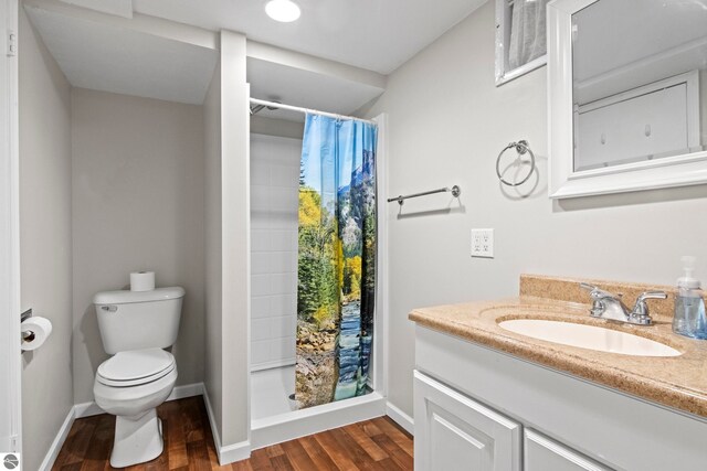 8695 S Maple City Rd, Maple City, MI 49664 - full bath featuring toilet, vanity, wood finished floors, curtained shower, and baseboards