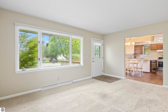 8695 S Maple City Rd, Maple City, MI 49664 - unfurnished living room featuring a baseboard heating unit, carpet floors, baseboards, and a chandelier