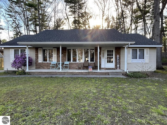 302 Huron St, Traverse City, MI 49686 - ranch-style house featuring brick siding, a porch, roof with shingles, and a front yard