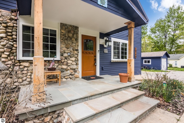 10190 S E Torch Lake Dr, Alden, MI 49612 - view of exterior entry with stone siding and a porch
