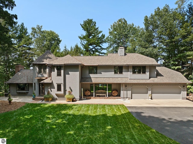 4283 Maitland Rd, Williamsburg, MI 49690 - view of front of property with asphalt driveway, a chimney, a balcony, and a front yard