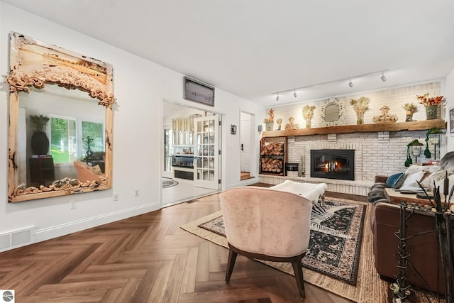 4283 Maitland Rd, Williamsburg, MI 49690 - living room featuring a brick fireplace, rail lighting, and baseboards