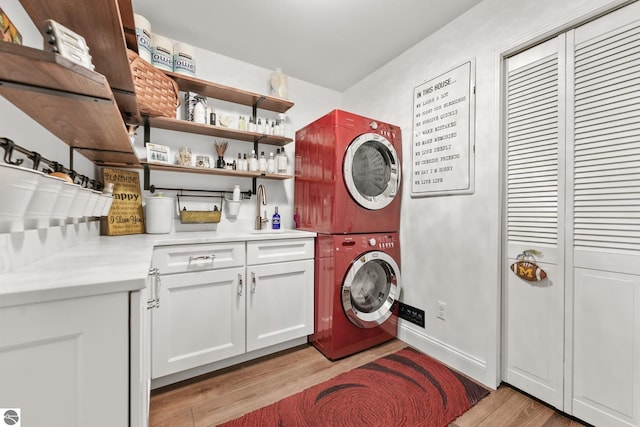 4283 Maitland Rd, Williamsburg, MI 49690 - laundry area featuring stacked washer and clothes dryer, cabinet space, and light wood-style flooring