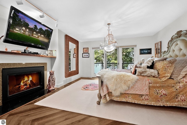 4283 Maitland Rd, Williamsburg, MI 49690 - bedroom with access to exterior, rail lighting, a lit fireplace, wood finished floors, and baseboards