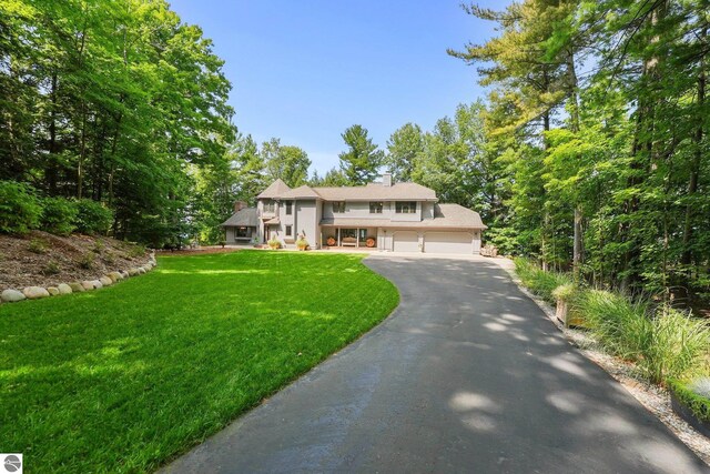 4283 Maitland Rd, Williamsburg, MI 49690 - view of front of house with driveway, a garage, and a front yard