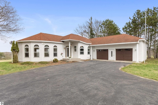 2769 White Rd, Frankfort, MI 49635 - mediterranean / spanish-style house featuring an attached garage, driveway, stucco siding, and a shingled roof