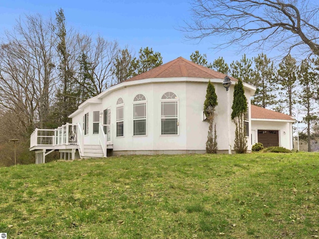 2769 White Rd, Frankfort, MI 49635 - view of property exterior with a garage, stucco siding, a lawn, a wooden deck, and roof with shingles